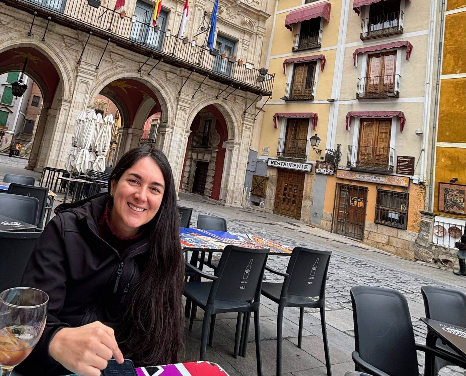 A Colombian woman with a glass of vermouth sits outside at a Spanish cafe.